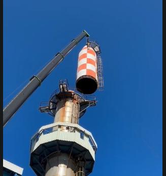 Demolición de chimenea industrial con grúa