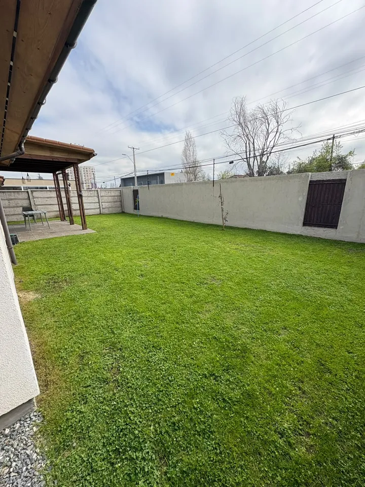 Patio amplio con césped parejo y pérgola